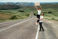 A couple hitchhiking. A man and a woman catch a car by the road. A young couple votes on the road.