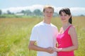 Couple hold hands, grass in field near village