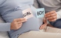 Couple holding BOY and GIRL cards in hands near pregnant belly Royalty Free Stock Photo