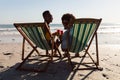 Couple holding cocktail glasses while relaxing in a beach chair on the beach Royalty Free Stock Photo