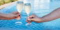 Couple holding glasses of champagne making a toast by the pool Royalty Free Stock Photo