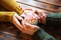Couple holding hands around a cup of hot chocolate cocoa with heart shaped marshmallow on top