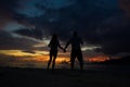 Couple holding hands on the beach with a beautiful sunset in background Royalty Free Stock Photo