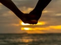 Couple holding hands on beautiful sunset background at the beach Royalty Free Stock Photo