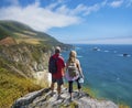 Couple holding hands on hiking trip resting on top of the mountain looking at ocean view. Royalty Free Stock Photo