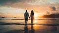 Couple holding hands and looking at beautiful sunset on the beach Royalty Free Stock Photo
