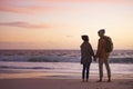 Couple, holding hands and love at sunset by water, ocean waves and peace for romance in relationship. People, back and Royalty Free Stock Photo