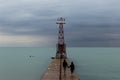 Couple holding hands walking along concrete pier jetty along Lake Michigan