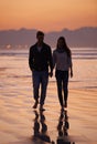 Couple, holding hands and walking on beach for sunset, nature and travel with bonding for love and commitment outdoor Royalty Free Stock Photo