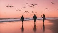 A couple holding hands and walking on a beach at sunset. The sky is orange and pink, and the ocean is calm. There Royalty Free Stock Photo