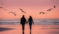 A couple holding hands and walking on a beach at sunset. The sky is orange and pink, and the ocean is calm. There Royalty Free Stock Photo