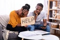 Couple Holding Help Sign While Calculating Bills