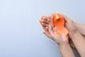 Couple holding orange ribbon on light grey background, top view with space for text. Multiple sclerosis awareness Royalty Free Stock Photo