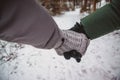 Couple holds hands in mittens walking on the path in the snowy winter forest Royalty Free Stock Photo