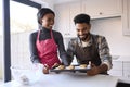 Couple At Home Baking Cookies Together In Kitchen 