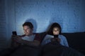 Couple at home in bed late at night using mobile phone in relationship communication problem Royalty Free Stock Photo