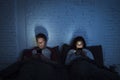 Couple at home in bed late at night using mobile phone in relationship communication problem