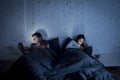 Couple at home in bed late at night using mobile phone in relationship communication problem