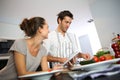 Couple at home cooking dish with tablet Royalty Free Stock Photo