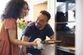 Couple At Home With Man With Down Syndrome And Woman Taking Pizza Out Of Oven In Kitchen Royalty Free Stock Photo