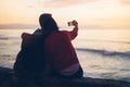 Couple hugging on background beach ocean sunrise, take photos on mobile smartphone, two romantic people cuddling and looking on vi Royalty Free Stock Photo