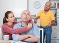 Couple hugging after conflict, worried elderly man on backgroud Royalty Free Stock Photo