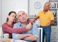 Couple hugging after conflict, worried elderly man on backgroud Royalty Free Stock Photo