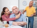 Couple hugging after conflict, worried elderly man on backgroud Royalty Free Stock Photo