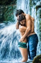 Couple hugging and kissing under waterfall Royalty Free Stock Photo