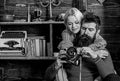 Couple hugs in wooden vintage interior. Man with beard, photographer on busy face holds old fashioned camera. Couple in