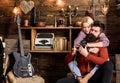 Couple hugs in wooden vintage interior. Man with beard, photographer on busy face holds old fashioned camera. Vintage
