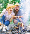 Couple hungry tourists roasting sausages on sticks nature background. Couple in love camping forest roasting sausage at Royalty Free Stock Photo