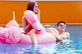 Couple with inflatable flamingo on swimming pool