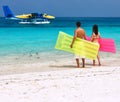 Couple with inflatable rafts looking at seaplane on beach