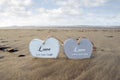Couple of inscribed wooden love hearts in the sand