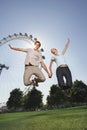 Couple Jumping In Air Against London Eye At Park