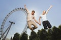 Couple Jumping In Air Against London Eye At Park