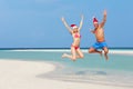 Couple Jumping On Beach Wearing Santa Hats Royalty Free Stock Photo