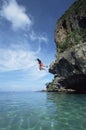 Couple jumping from cliffs into the sea