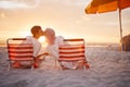 Couple, kiss and beach chairs by a ocean sunset with love, happiness and care on vacation. Sea, sunshine and kissing of Royalty Free Stock Photo