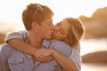 Couple, kiss and love in hug at beach, ocean waves and peace for romance in relationship. People, affection and security Royalty Free Stock Photo