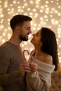 couple kissing and showing the heart-shaped figure of candy canes candies