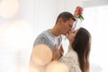 Happy couple kissing under mistletoe bunch at home, bokeh effect Royalty Free Stock Photo