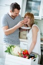 Couple in kitchen, eating bread with tomato