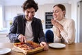 Couple In Kitchen At Home Eating Homemade Pizza Sitting At Counter