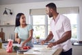 Couple In Kitchen At Home Preparing Homemade Pizzas Together