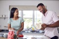 Couple In Kitchen At Home Preparing Homemade Pizzas Together