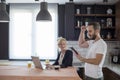 Couple in kitchen in the morning. Happy excited man cheering satisfied with results on laptop Royalty Free Stock Photo