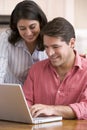 Couple in kitchen with paperwork using laptop Royalty Free Stock Photo