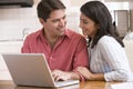 Couple in kitchen using laptop and smiling Royalty Free Stock Photo